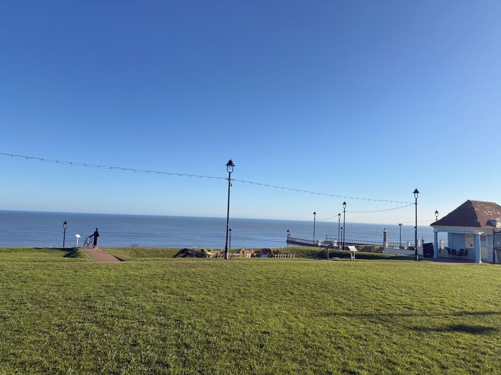 An outdoor area with grass and a path leading to the ocean at Pebble Cottage in Whitby