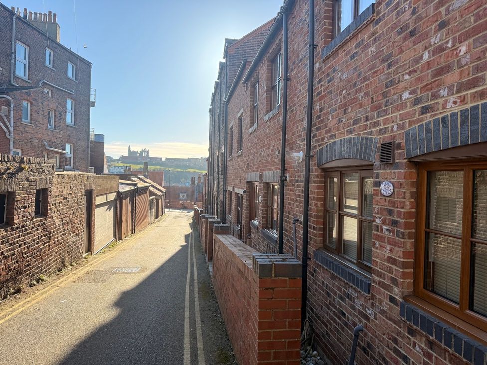 An alley with brick buildings and windows at Pebble Cottage in Whitby