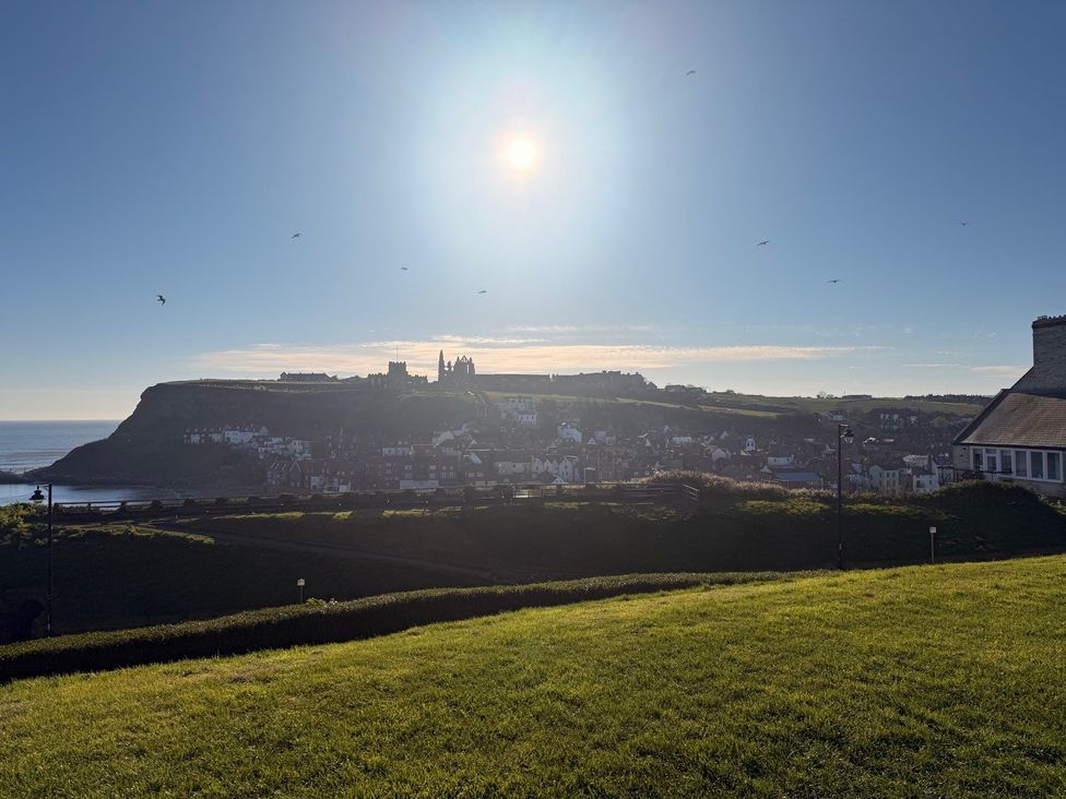 A view of a coastal landscape with houses and grass at Pebble Cottage in Whitby