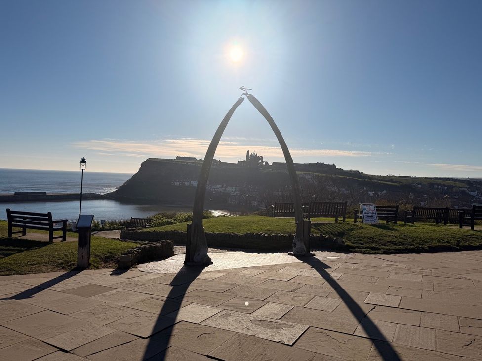 An outdoor space with a whale arch and benches at Pebble Cottage in Whitby