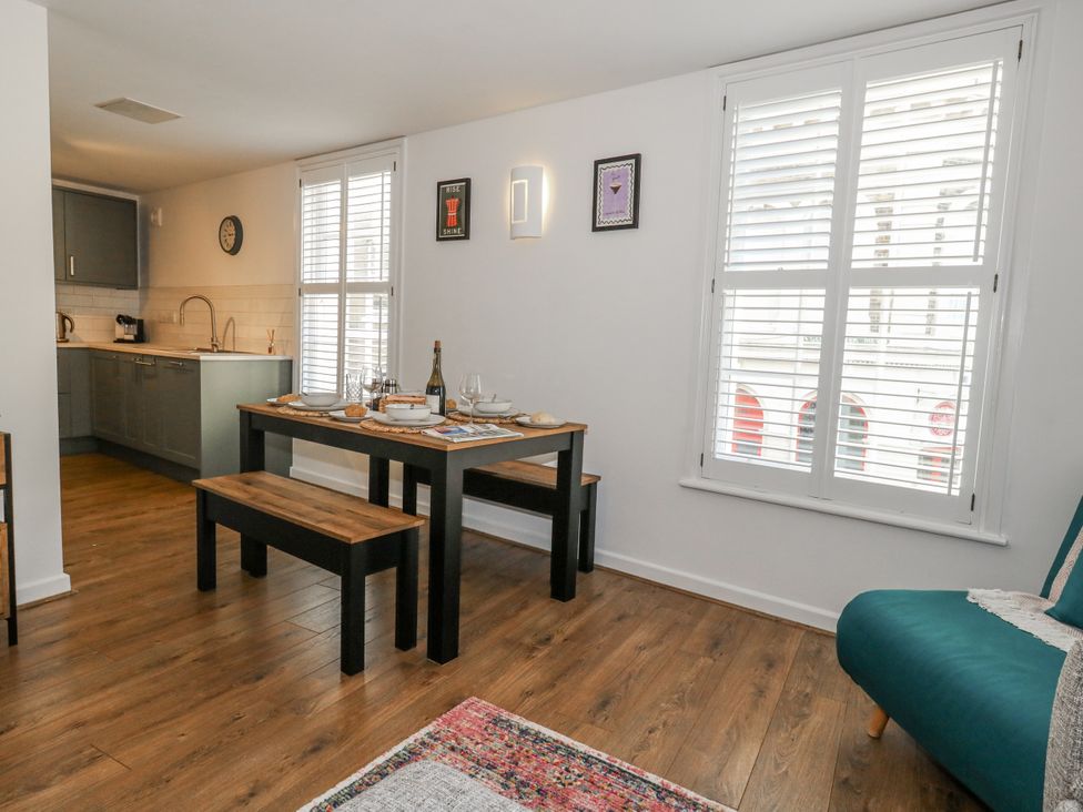 A dining room with a table and kitchen area at Betty's Buoy in Weymouth