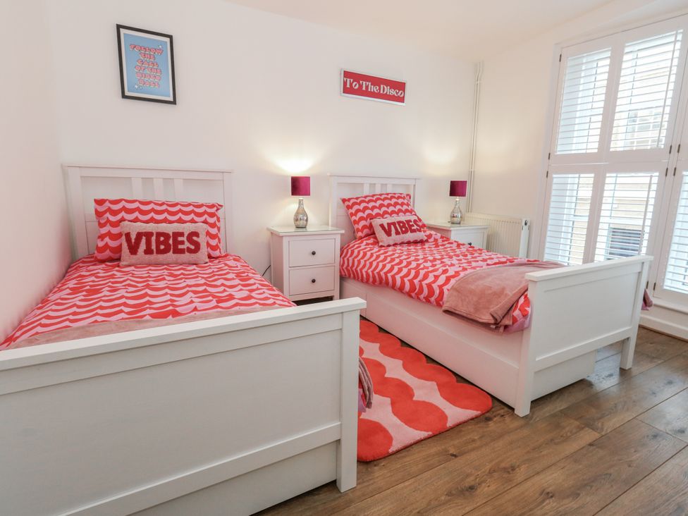 A bedroom with two beds and a bedside table at Betty's Buoy in Weymouth