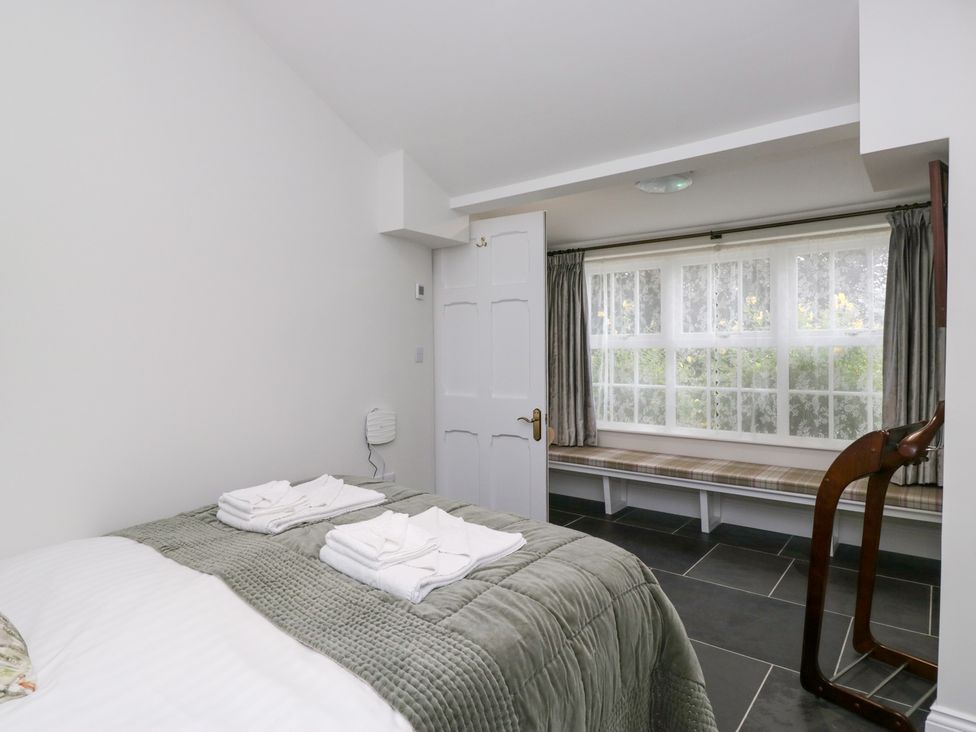 A bedroom with a bed and window seat at Pippins in Ambleside