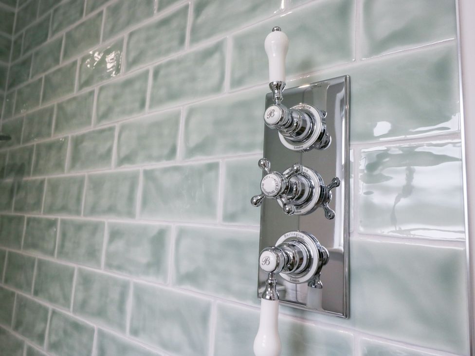 A shower control panel on green tiled wall at Pippins Ambleside