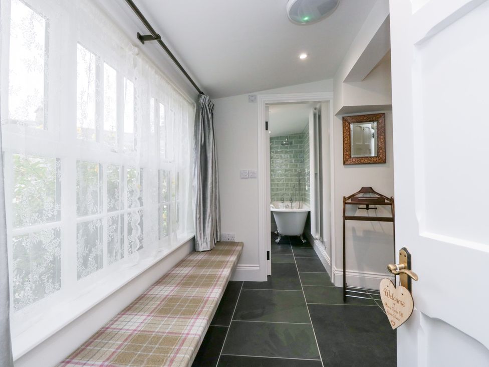 A hallway with a bench and access to a bathroom at Pippins Ambleside