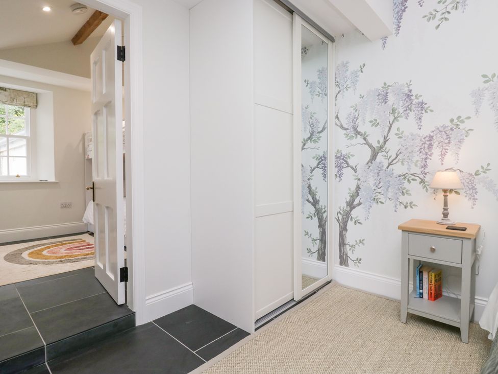 A bedroom with a wardrobe and side table at Pippins in Ambleside