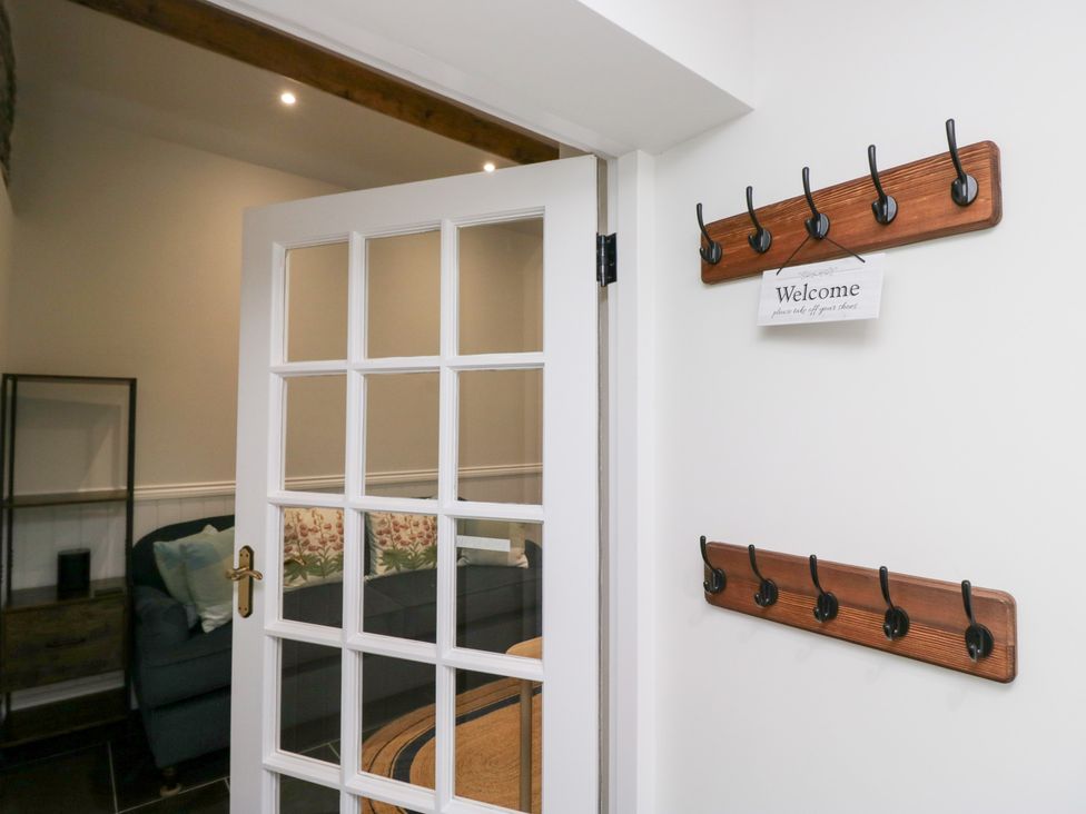 An entrance with coat hooks and a welcome sign at Pippins in Ambleside