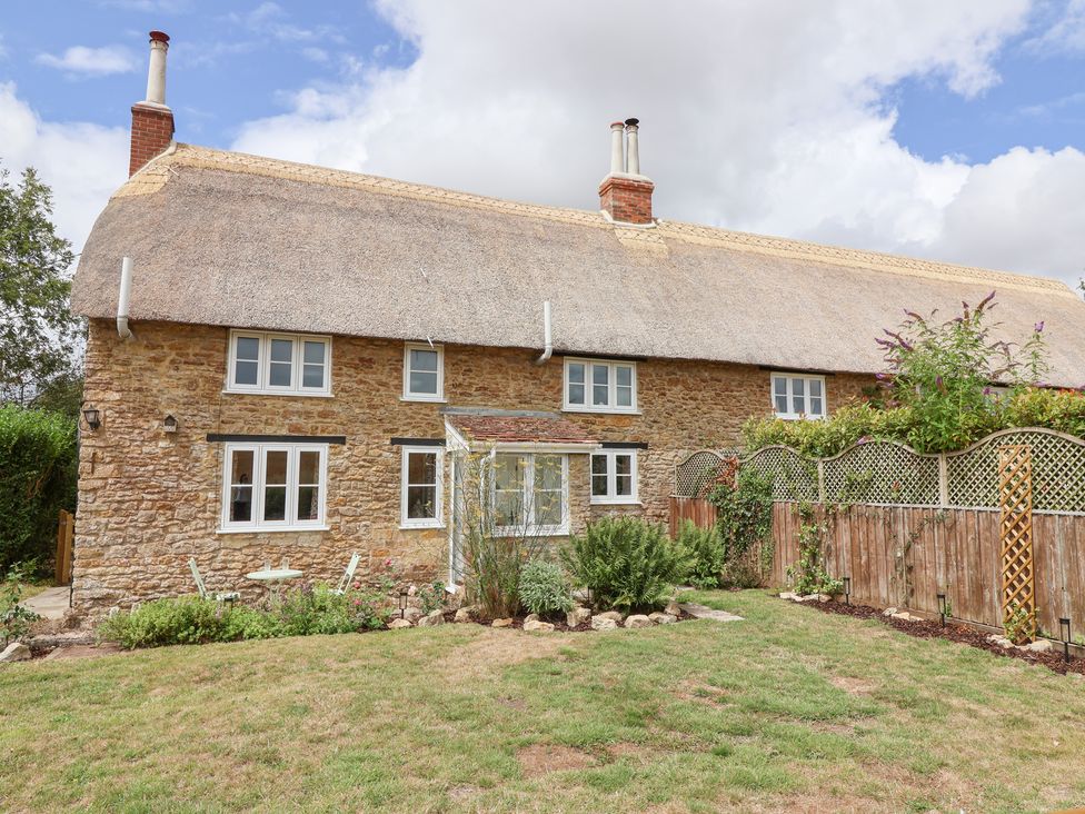 A house with a thatched roof and garden at Thatchers End in Sherborne