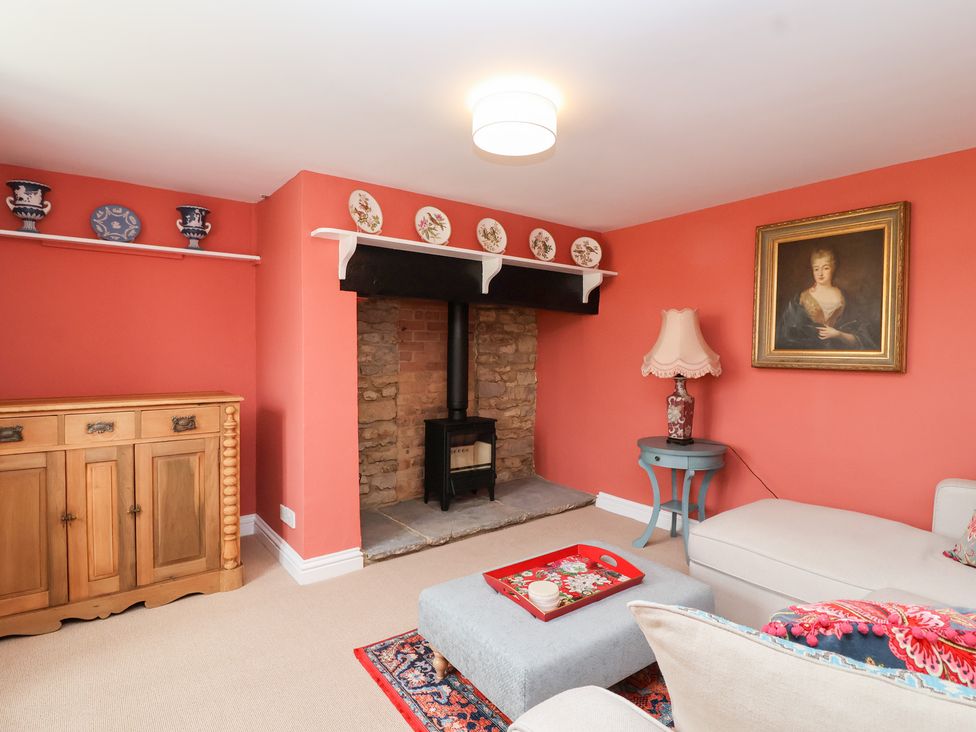 A living room with a fireplace and shelves at Thatchers End in Sherborne