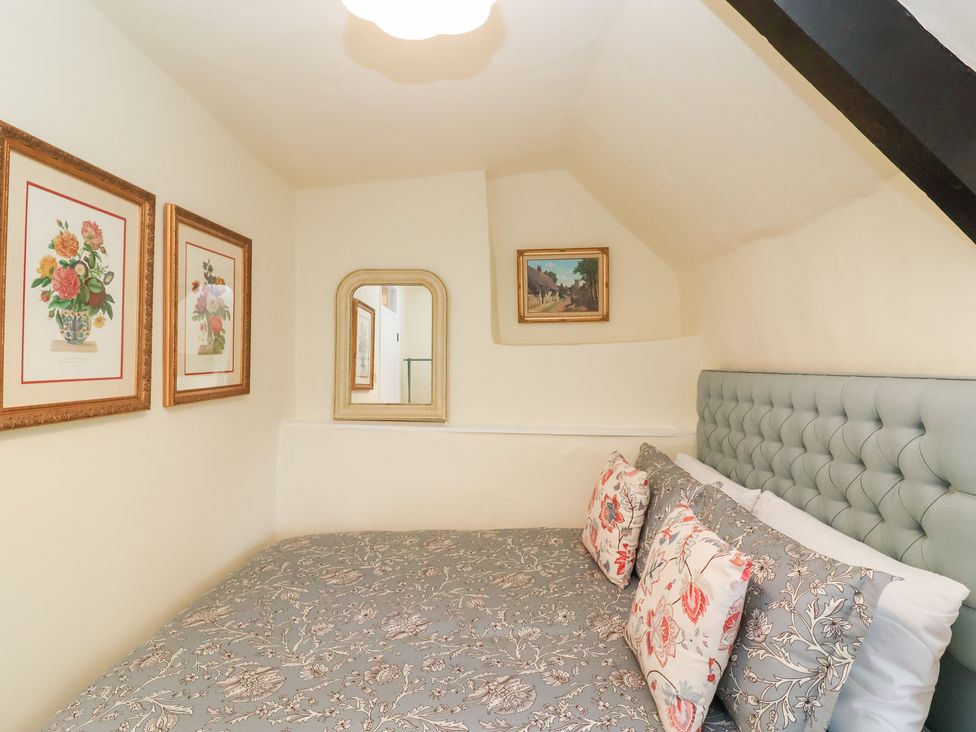 A bedroom with a bed and wall art at Thatchers End in Sherborne