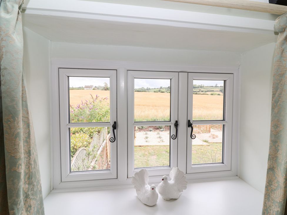 A window with decorative birds overlooking fields at Thatchers End in Sherborne