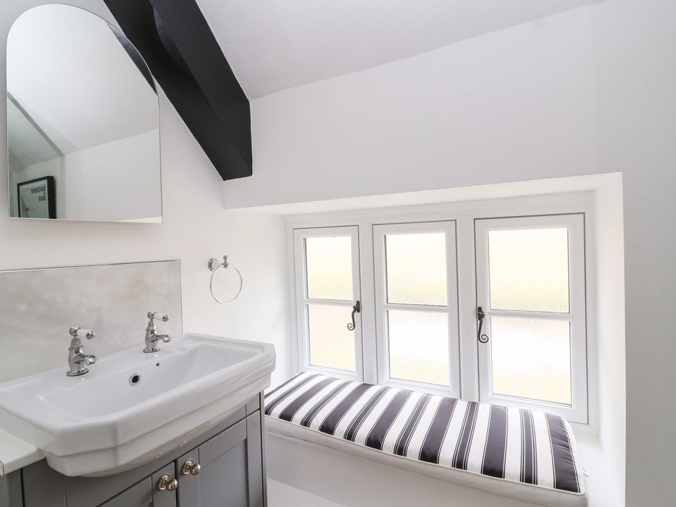 A bathroom with a sink and multiple windows at Thatchers End in Sherborne