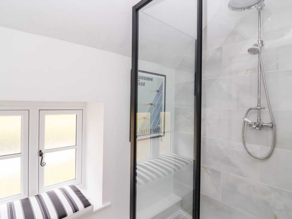 A bathroom with a shower enclosure and a window at Thatchers End in Sherborne