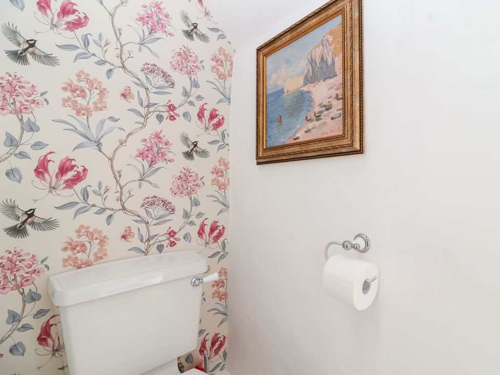A bathroom with a toilet and wallpaper at Thatchers End in Sherborne