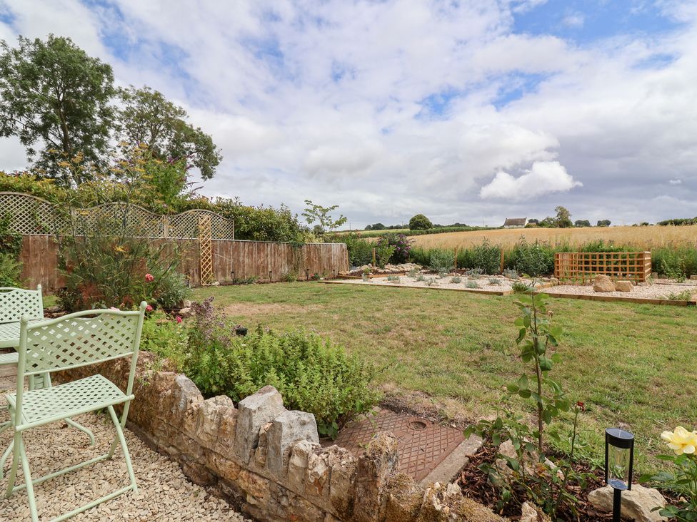 A garden area with grass, chairs, and flowerbeds at Thatchers End in Sherborne
