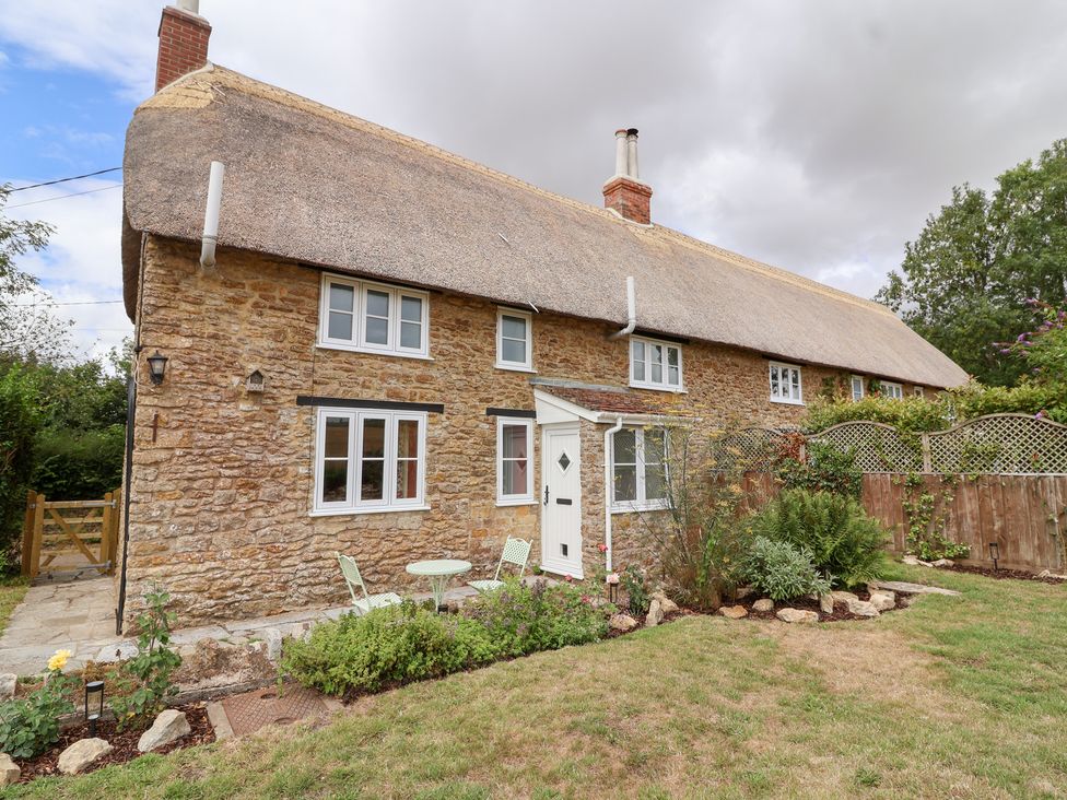 A house with a thatched roof and garden at Thatchers End in Sherborne