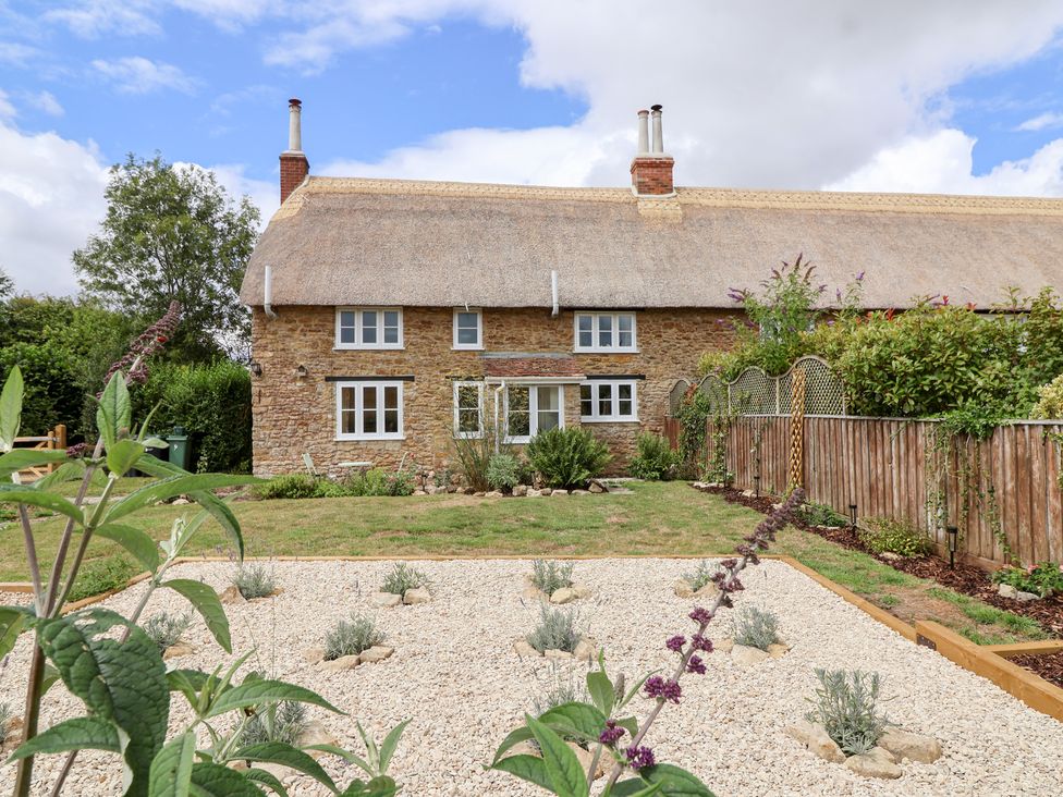 A house with a garden and a thatched roof at Thatchers End in Sherborne