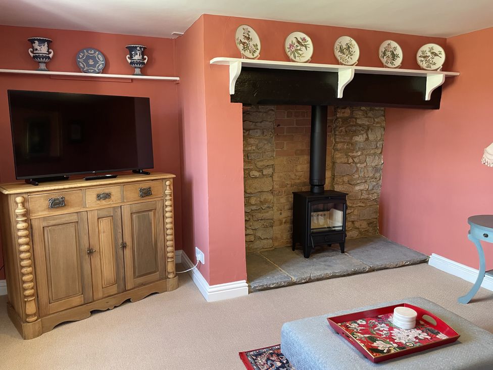 A living room with a television and wood stove at Thatchers End in Sherborne