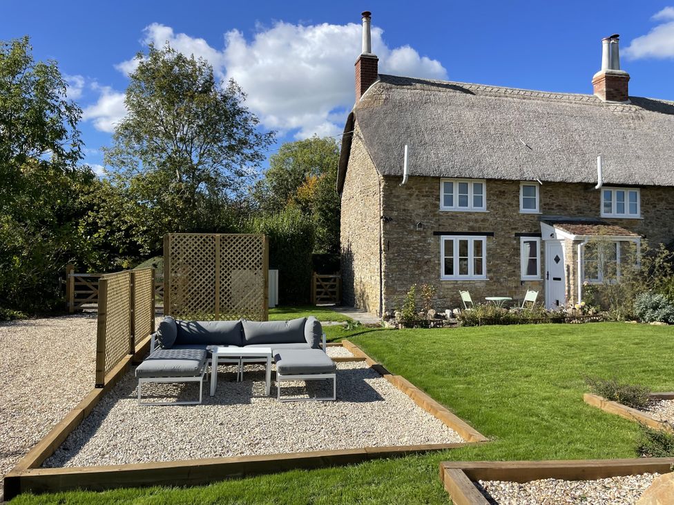 A garden with a house and outdoor furniture at Thatchers End in Sherborne