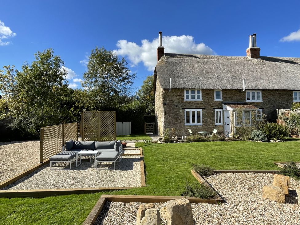 An outdoor garden with a sofa and fence at Thatchers End in Sherborne