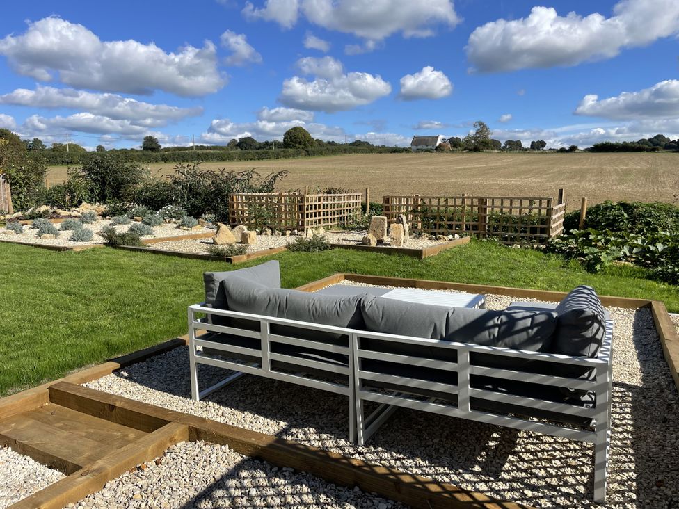A garden with a sofa and table at Thatchers End in Sherborne