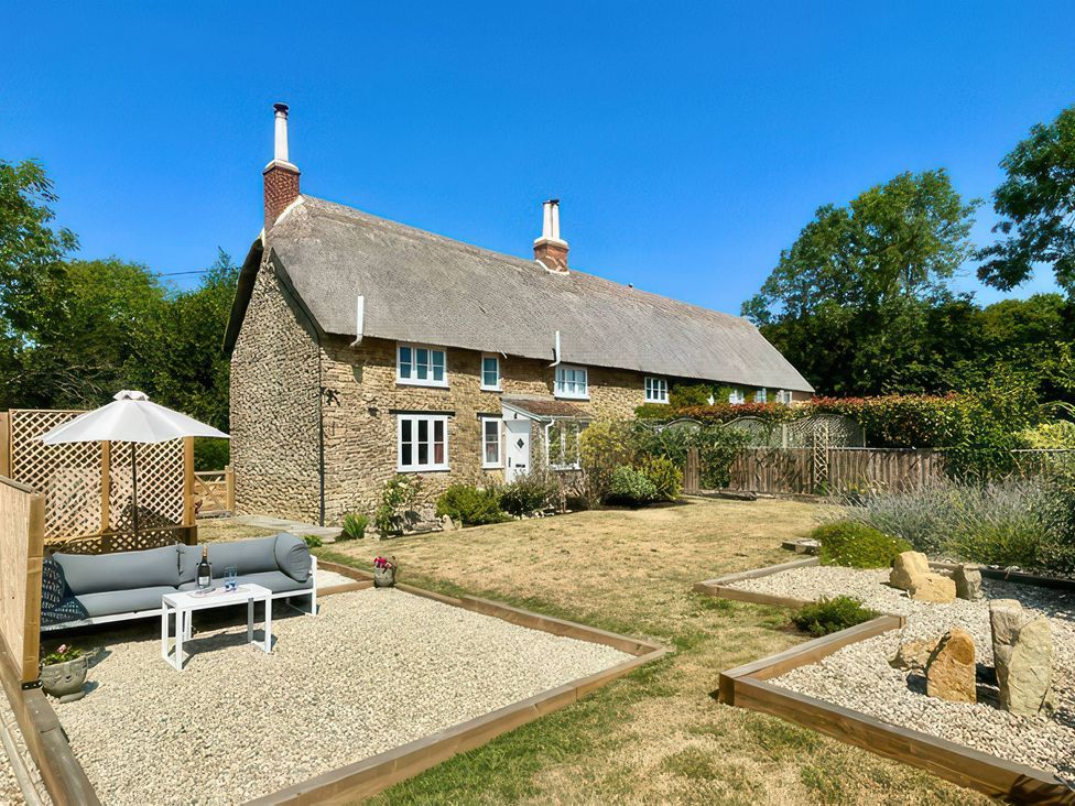 A house with a thatched roof and garden at Thatchers End in Sherborne