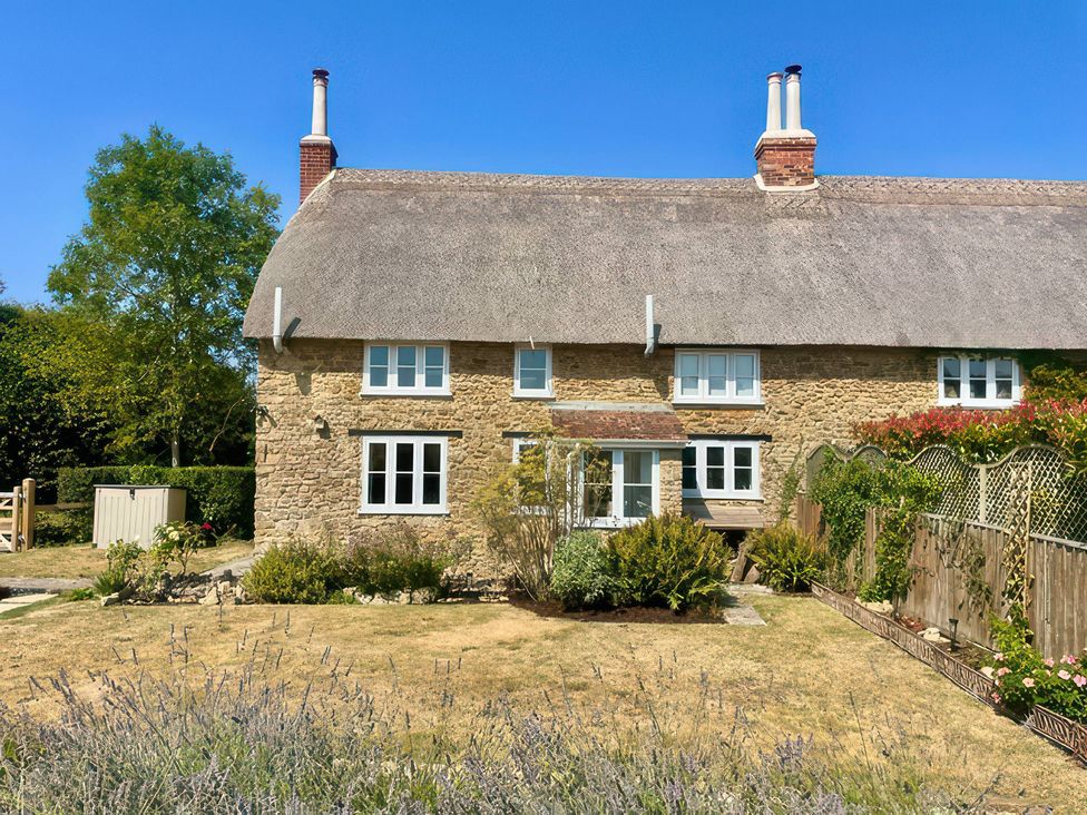 A house with a thatched roof and garden at Thatchers End in Sherborne