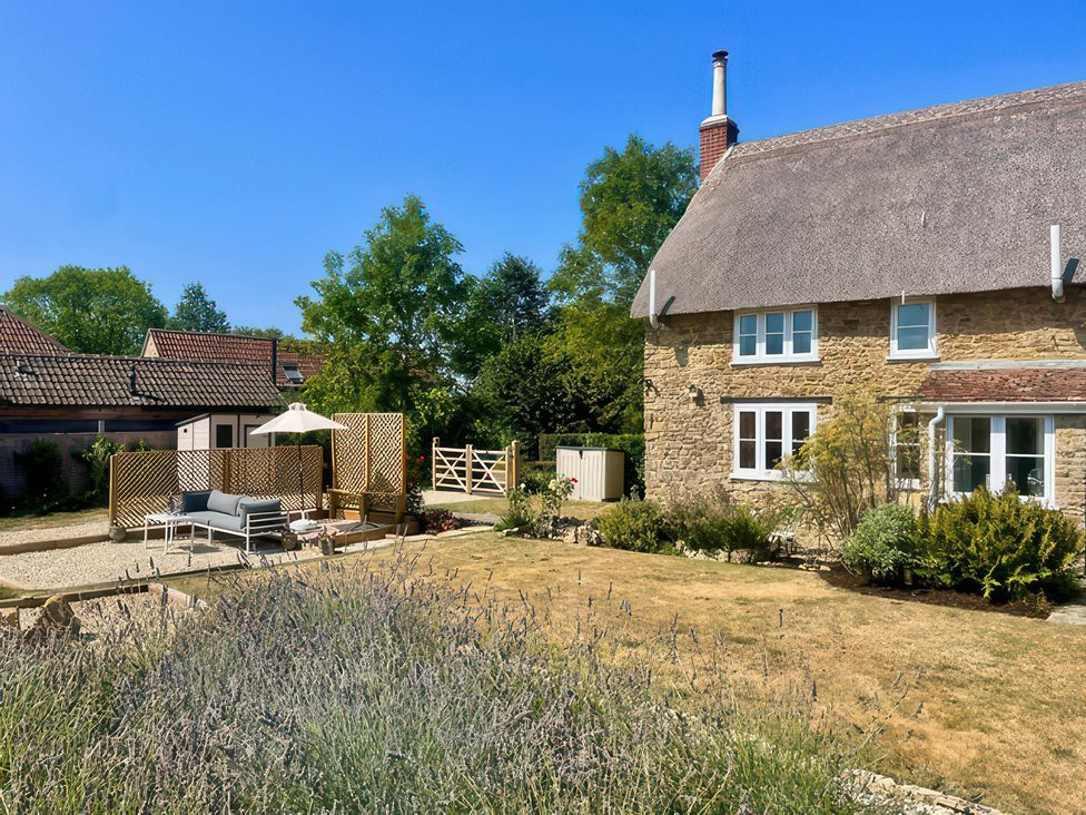 A house with a garden and patio furniture at Thatchers End Sherborne