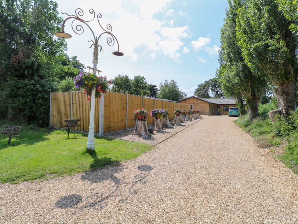 An outdoor area with a gravel driveway and a wooden cabin at Enchanted Cottage in Snettisham