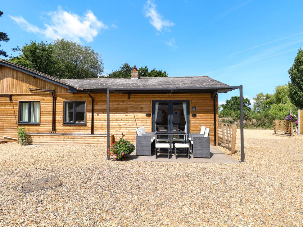 An outdoor patio area with a dining table and chairs at Rabbit Warren Lodge in Snettisham