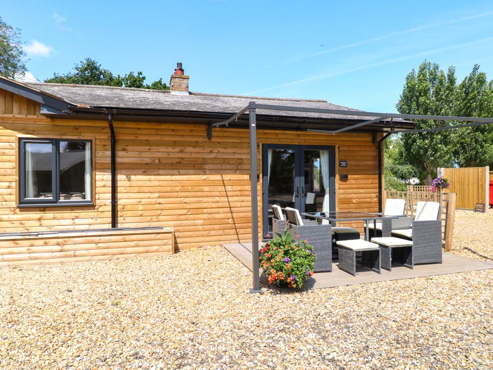 A house with patio furniture and flowers at Rabbit Warren Lodge in Snettisham