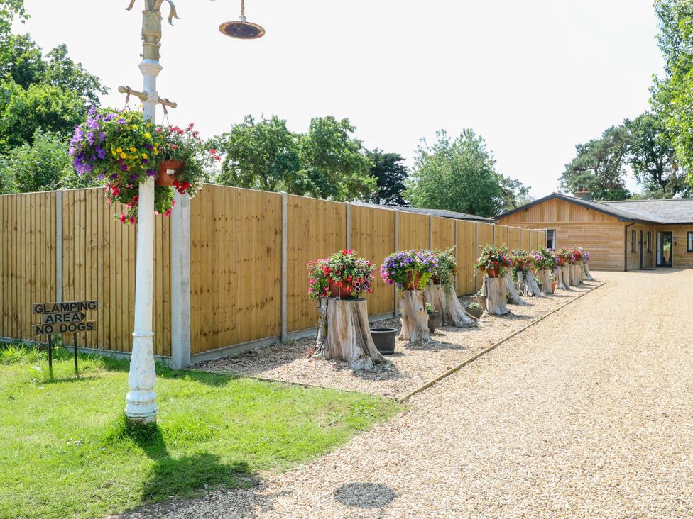 An outdoor glamping area with flower pots and a wooden fence at Rabbit Warren Lodge Snettisham