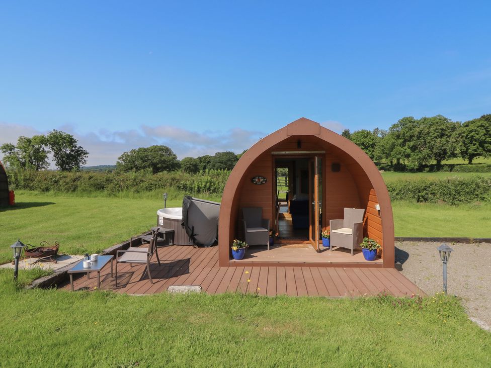 A glamping pod with a wooden deck and outdoor seating at Ty Twt Teifi in Tregaron