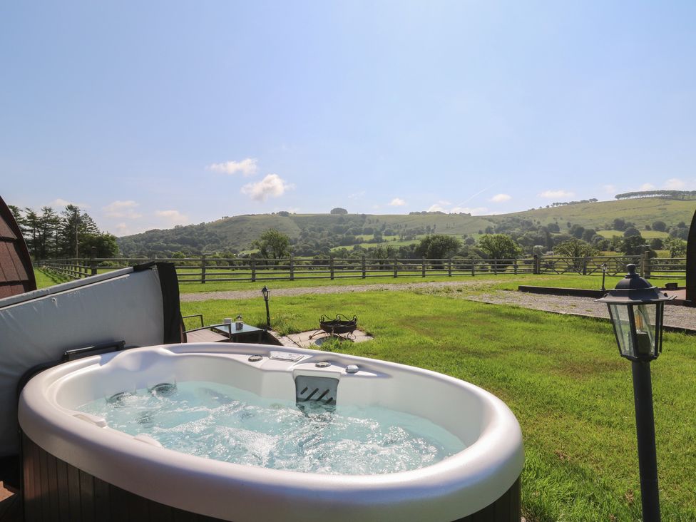 A hot tub on grass with a view of hills at Ty Twt Teifi in Tregaron