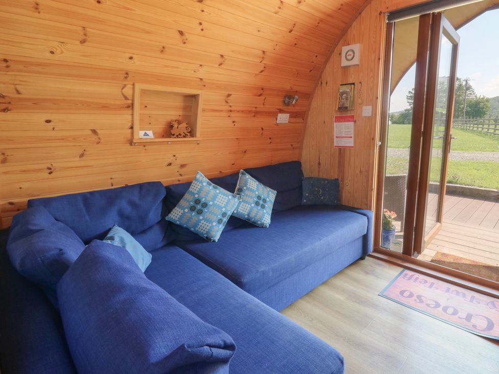 A snug with a blue sofa and wooden flooring at Ty Twt Teifi in Tregaron