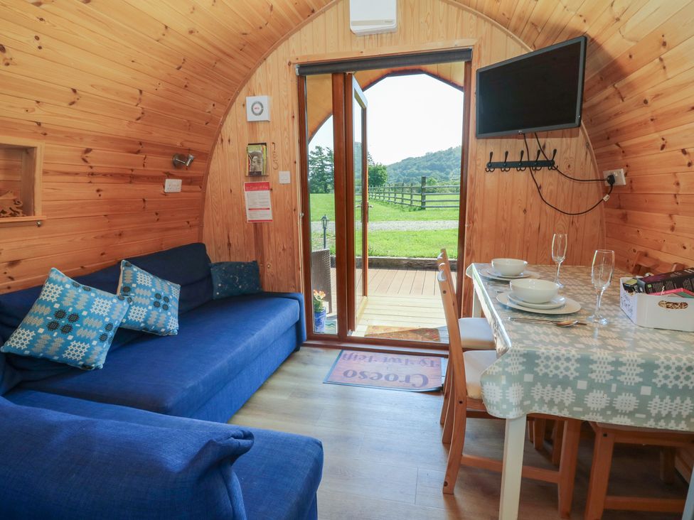 A living room with a sofa and dining table at Ty Twt Teifi in Tregaron