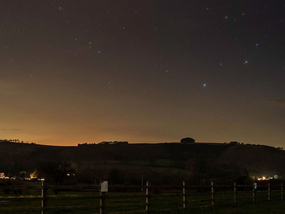 A view of stars and hills with lights at Ty Twt Teifi in Tregaron