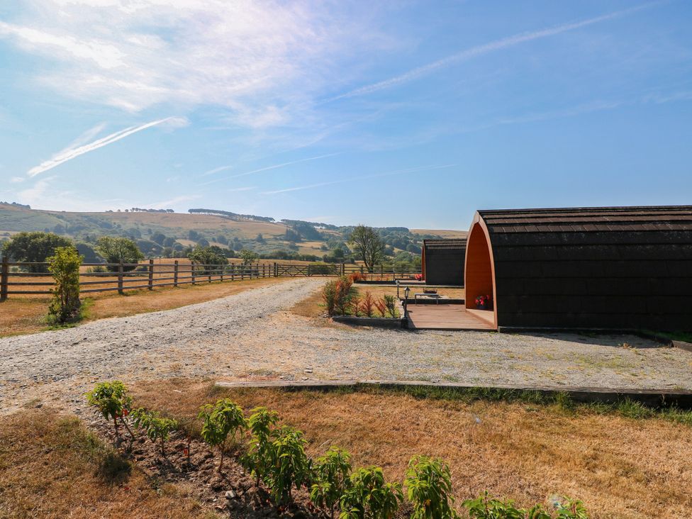 A view of wooden pods and a gravel path at Ty Twt Teifi in Llanddewi-Brefi