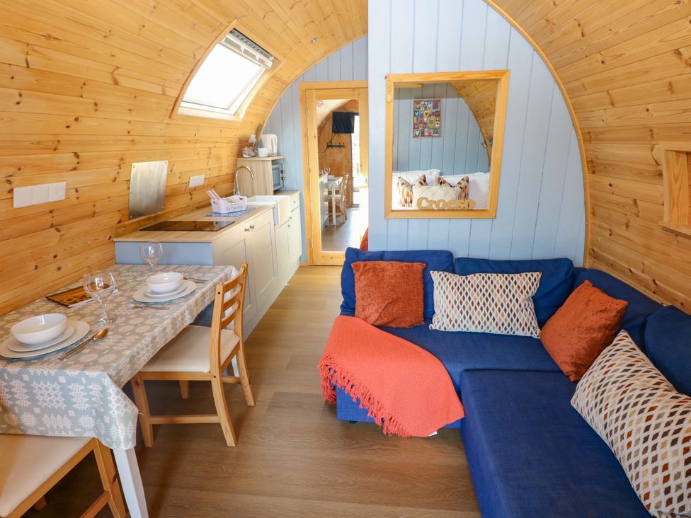 A living room with a sofa and dining area at Ty Twt Teifi in Llanddewi-Brefi