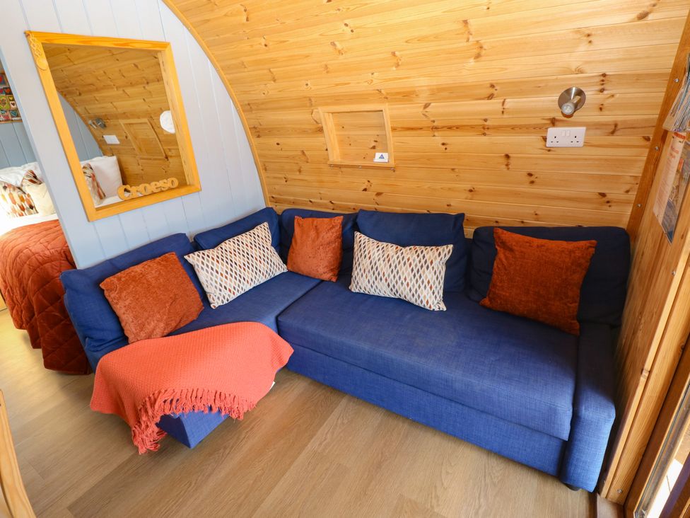 A snug with a blue sofa and throw blanket at Ty Twt Teifi, Llanddewi-Brefi