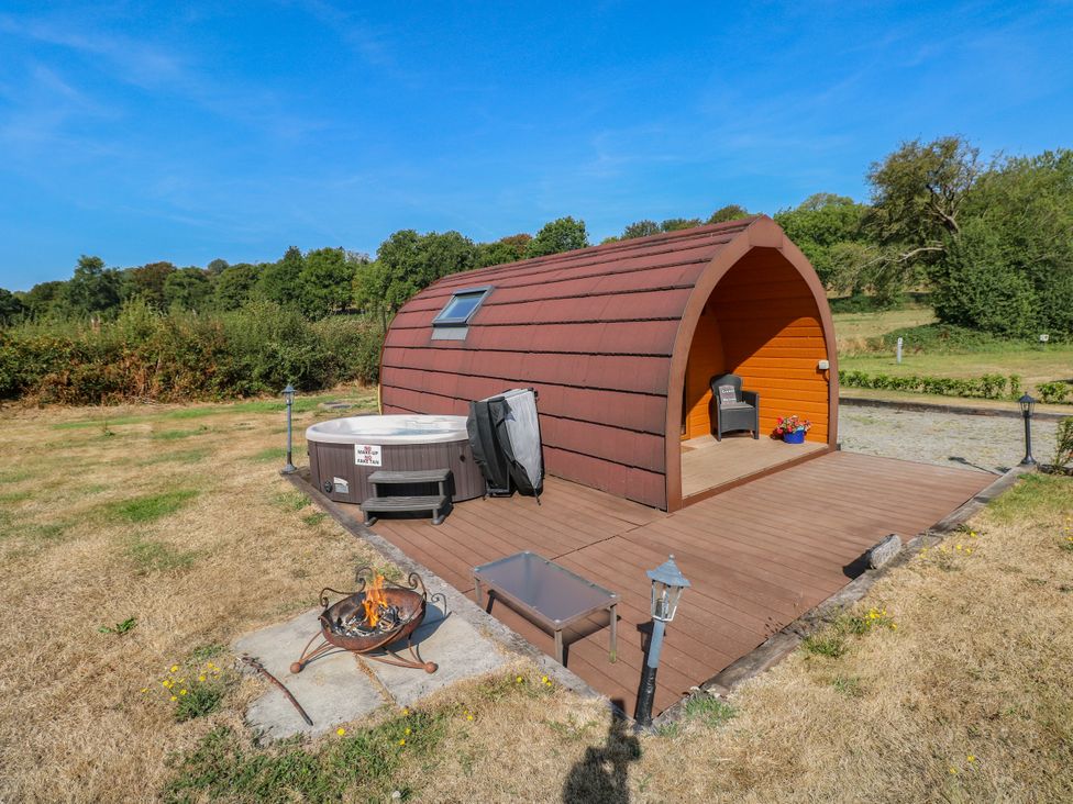 An outdoor area with a hot tub and a pod structure at Ty Twt Teifi in Llanddewi-Brefi
