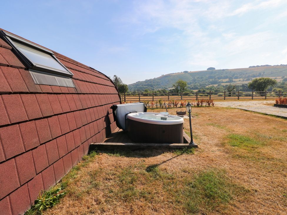 A hot tub with a fence and hill in the background at Ty Twt Teifi in Llanddewi-Brefi