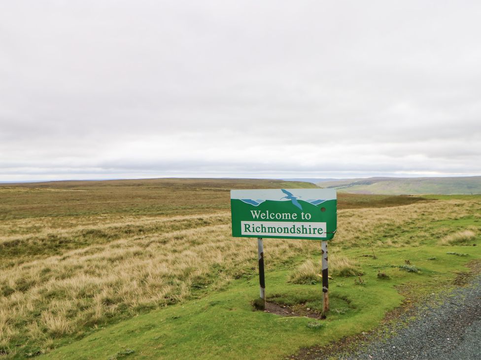 A welcome sign for Richmondshire with grass and clouds in the background
