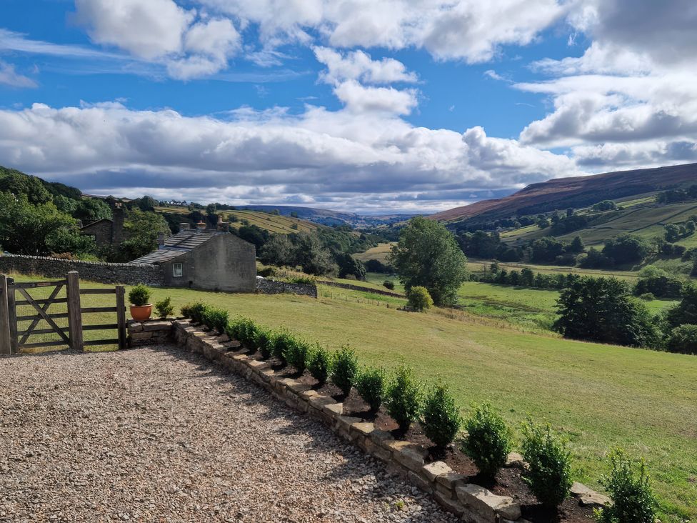 A view of a landscape with a gate and plants at Nick Jone in Reeth