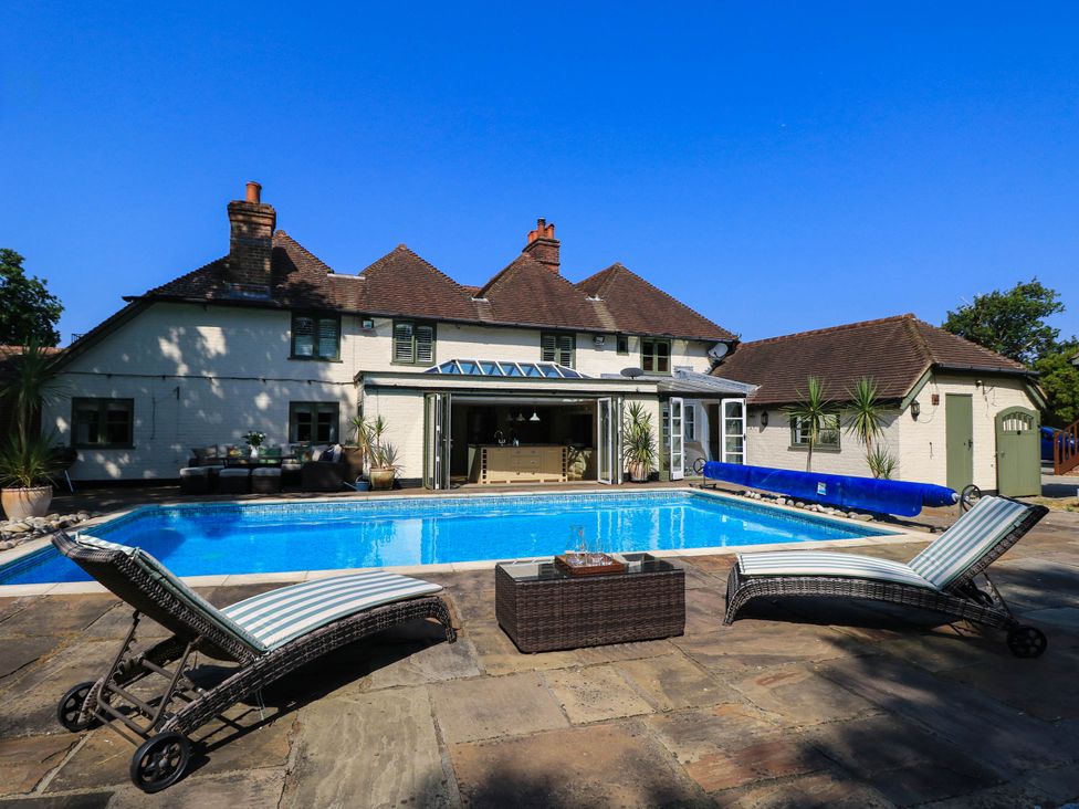 A swimming pool with lounge chairs and table at Beam Cottage in Warsash