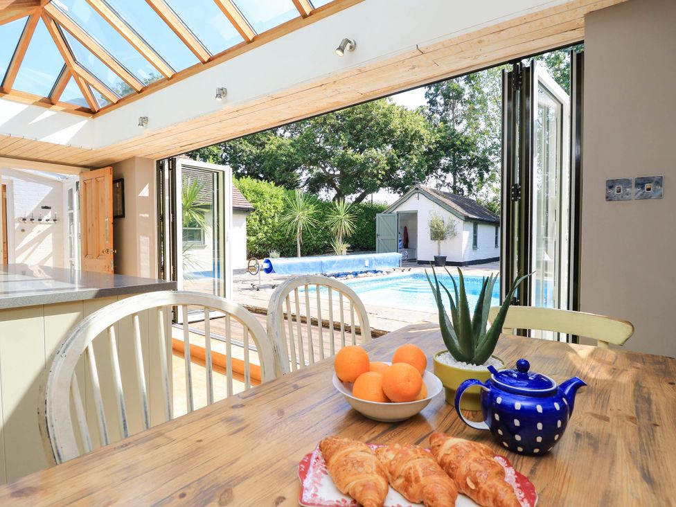 A kitchen with a view of the pool and garden at Beam Cottage in Warsash