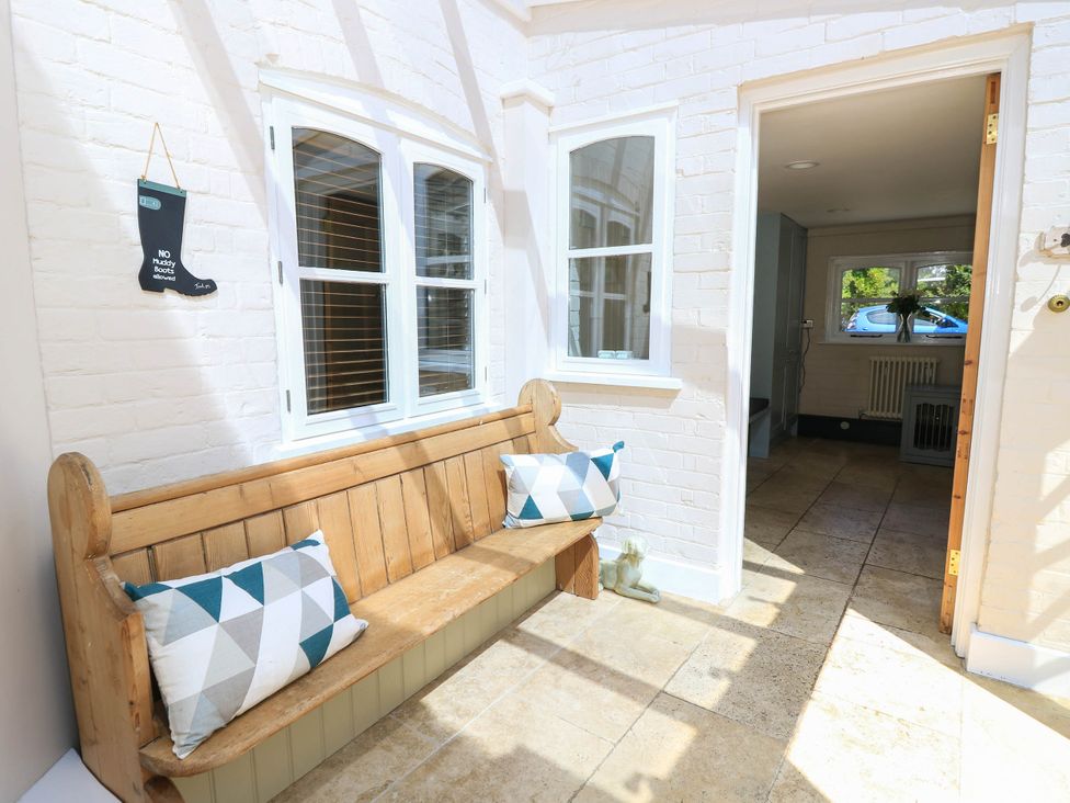 A hallway with a wooden bench and decorative pillows at Beam Cottage in Warsash
