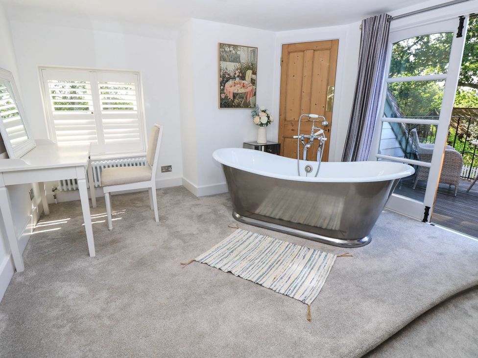 A bathroom with a bathtub, desk, and chair at Beam Cottage in Warsash