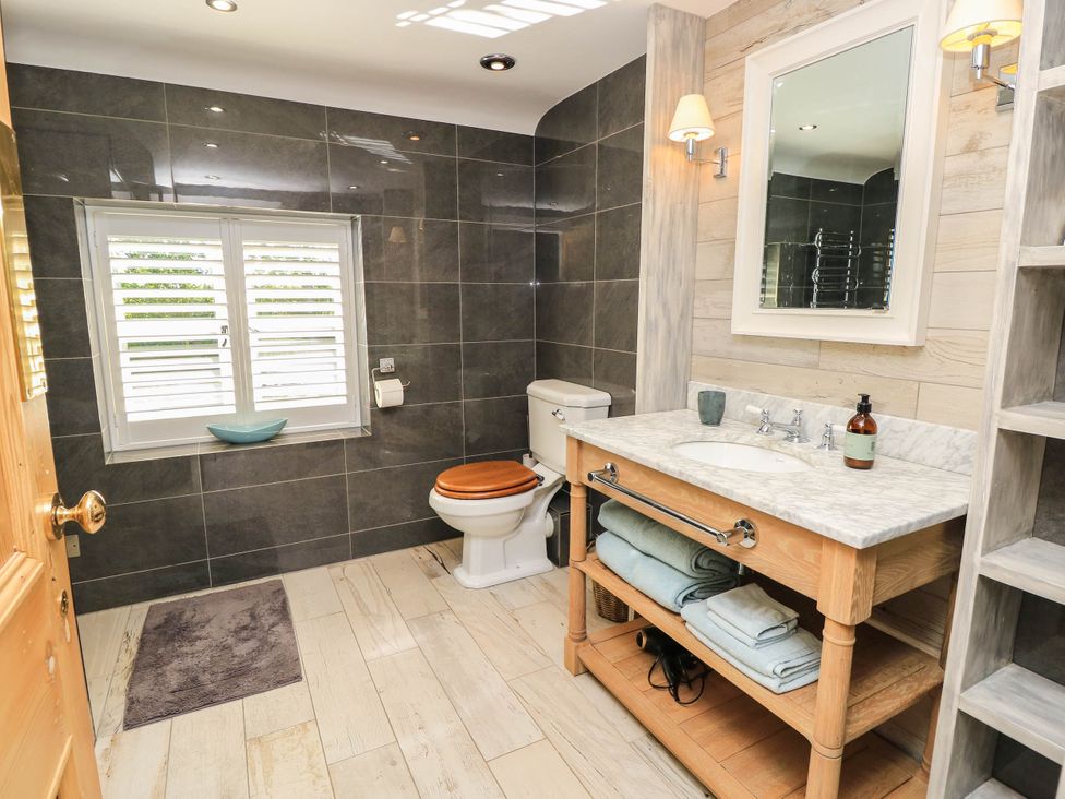 A bathroom with a sink, toilet, and shelves at Beam Cottage in Warsash
