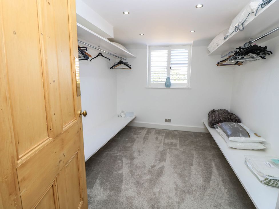 A dressing room with shelves and clothes hangers at Beam Cottage in Warsash